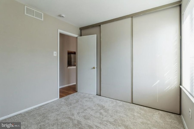 unfurnished bedroom with light colored carpet and a closet