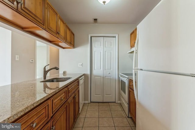 kitchen featuring white appliances, light tile patterned flooring, light stone countertops, and sink