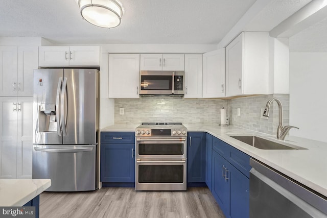 kitchen with appliances with stainless steel finishes, blue cabinetry, white cabinets, and sink