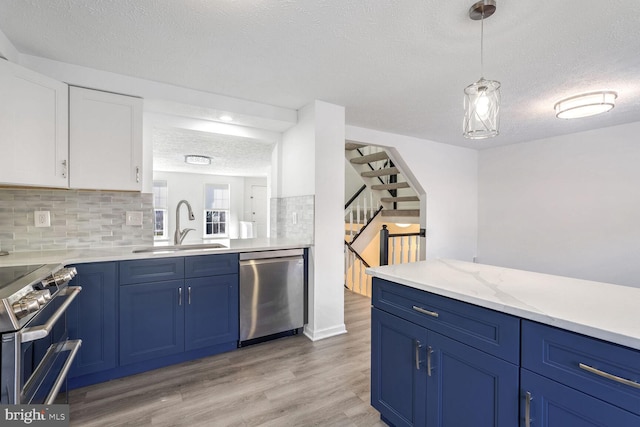 kitchen with appliances with stainless steel finishes, pendant lighting, white cabinets, blue cabinets, and sink