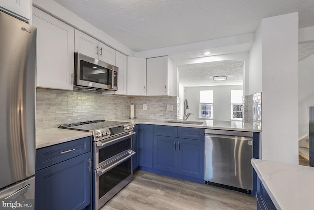 kitchen featuring appliances with stainless steel finishes, white cabinetry, blue cabinets, and sink