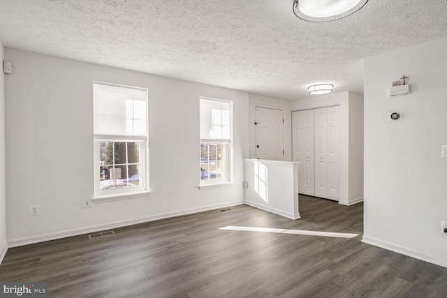 empty room with a textured ceiling and dark hardwood / wood-style floors