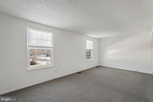 unfurnished room featuring a textured ceiling and dark colored carpet