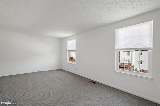 carpeted spare room with a textured ceiling