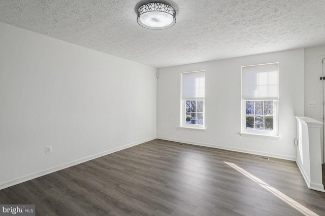 spare room featuring a textured ceiling and dark hardwood / wood-style flooring