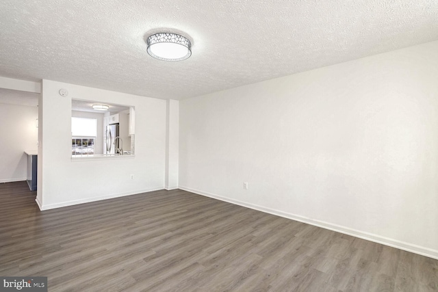 empty room featuring a textured ceiling and dark wood-type flooring