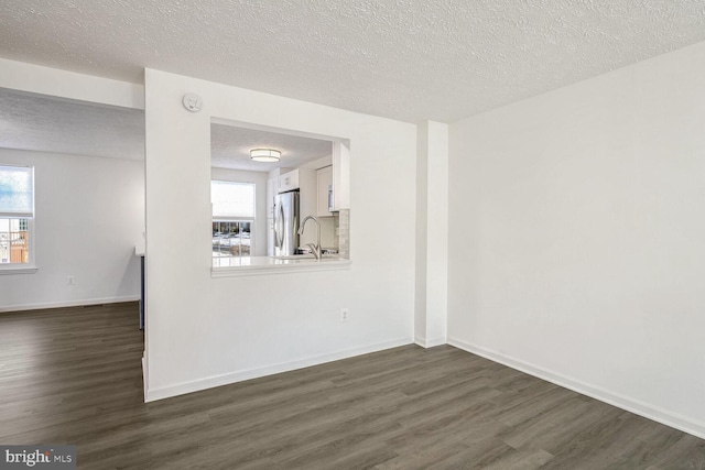 spare room with a textured ceiling, a wealth of natural light, and dark hardwood / wood-style floors