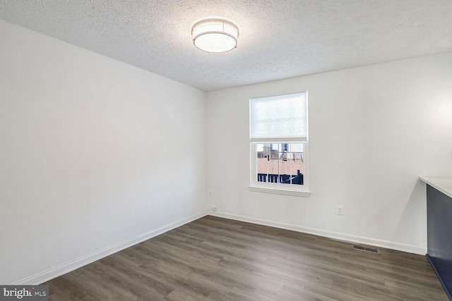 unfurnished room with a textured ceiling and dark hardwood / wood-style floors