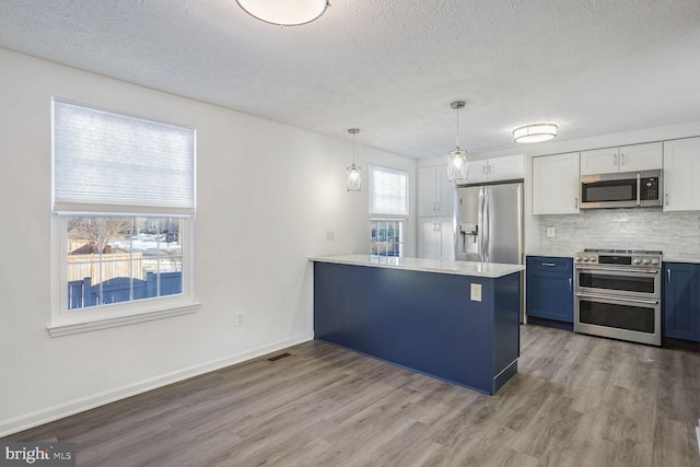 kitchen featuring stainless steel appliances, white cabinets, pendant lighting, and kitchen peninsula