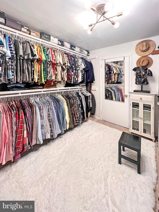 spacious closet with light colored carpet and a chandelier