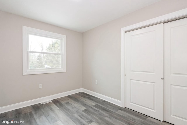 unfurnished bedroom featuring a closet and dark wood-type flooring