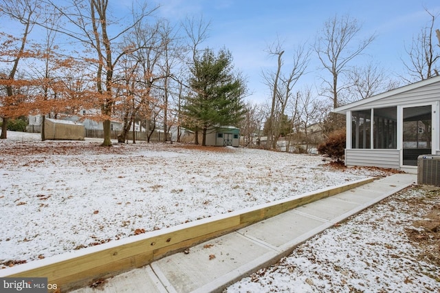 yard covered in snow with central air condition unit and a sunroom