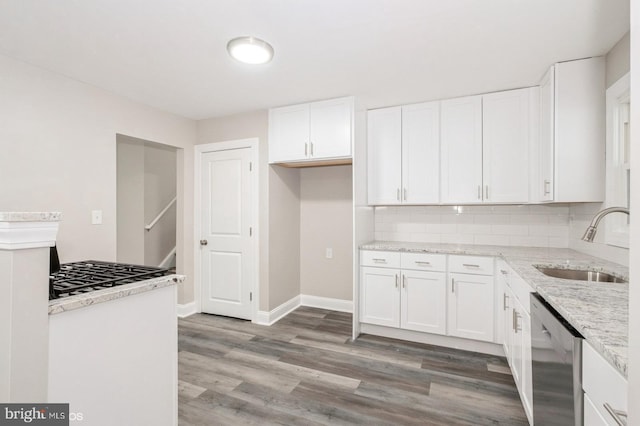 kitchen featuring light stone countertops, white cabinetry, sink, stainless steel dishwasher, and light wood-type flooring