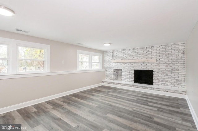 unfurnished living room featuring hardwood / wood-style flooring, plenty of natural light, and a brick fireplace