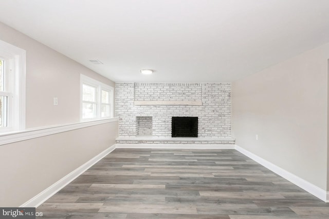 unfurnished living room featuring wood-type flooring and a brick fireplace