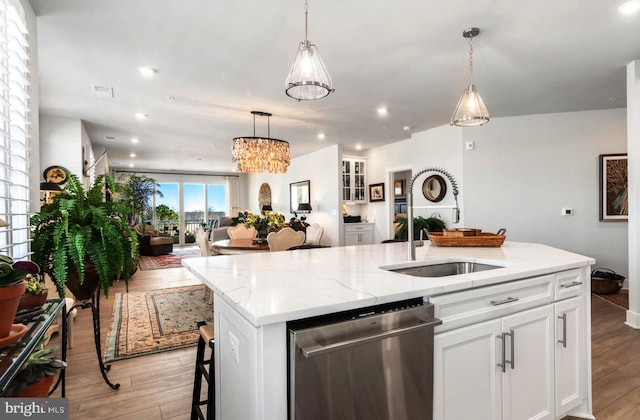 kitchen with stainless steel dishwasher, light hardwood / wood-style flooring, an island with sink, white cabinetry, and sink