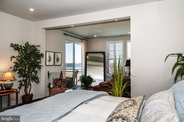 bedroom with hardwood / wood-style floors and a water view