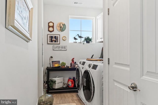 clothes washing area with cabinets, separate washer and dryer, and light hardwood / wood-style flooring