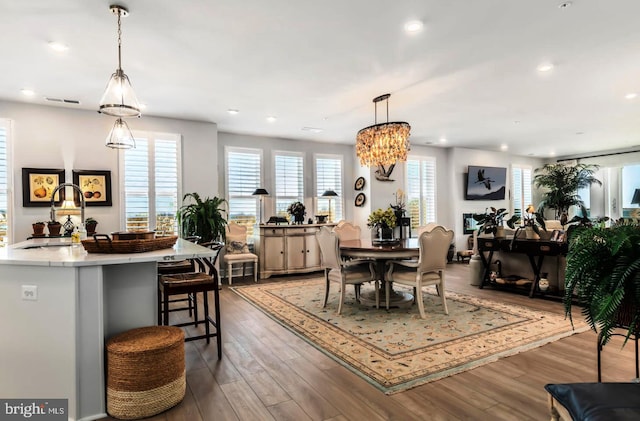 dining space with sink, a chandelier, and hardwood / wood-style flooring