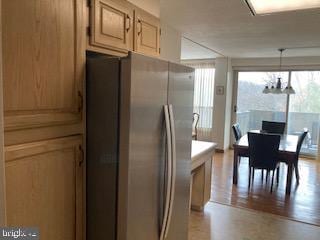 kitchen with stainless steel refrigerator, decorative light fixtures, a chandelier, and light brown cabinets