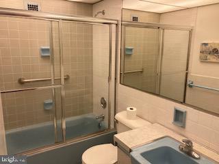 full bathroom featuring shower / bath combination with glass door, toilet, and sink