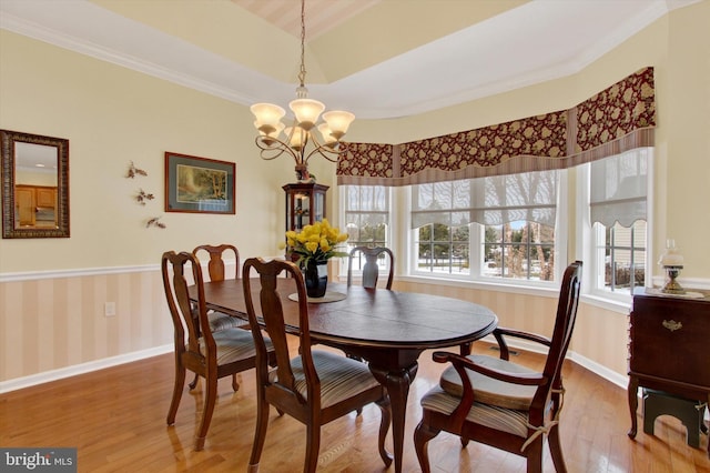 dining space featuring crown molding, wood-type flooring, and a notable chandelier