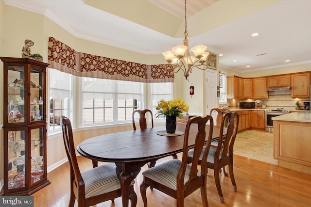 dining area with light wood-type flooring, crown molding, and an inviting chandelier