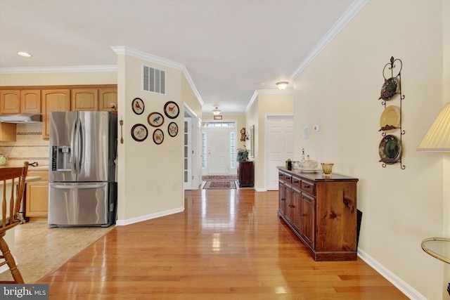 kitchen with stainless steel fridge, light hardwood / wood-style floors, tasteful backsplash, and ornamental molding