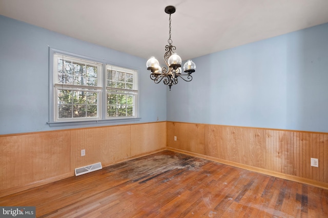 unfurnished room featuring a chandelier and hardwood / wood-style floors