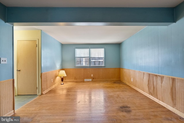 spare room with light hardwood / wood-style flooring and wood walls