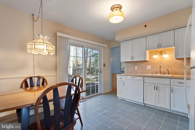 kitchen with pendant lighting, dishwasher, white cabinetry, sink, and backsplash