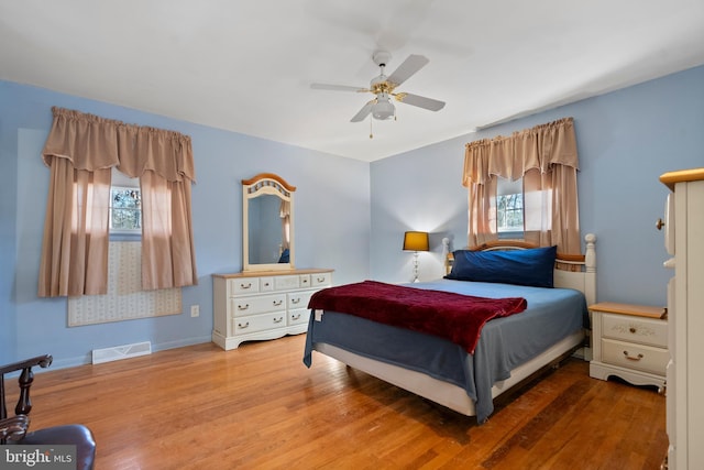 bedroom with ceiling fan, hardwood / wood-style floors, and multiple windows