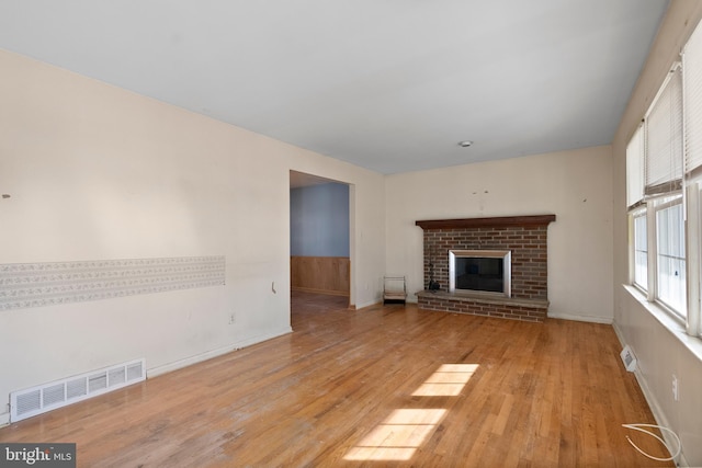 unfurnished living room featuring a fireplace and light hardwood / wood-style floors