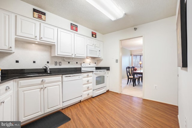 kitchen with white cabinetry, sink, white appliances, and light hardwood / wood-style flooring