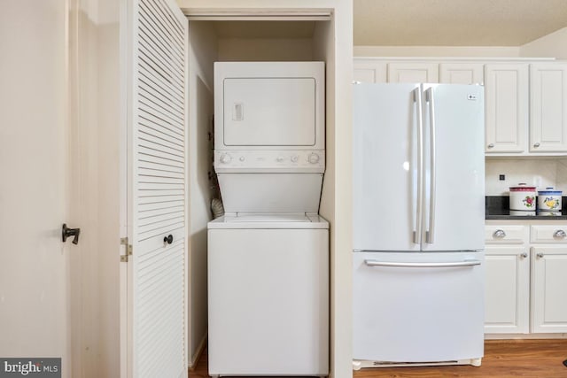 clothes washing area featuring stacked washer / dryer and hardwood / wood-style floors