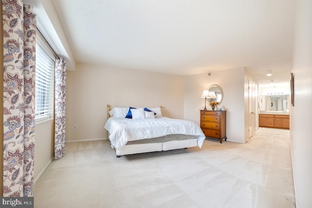 bedroom with ensuite bathroom and light colored carpet