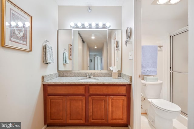 bathroom featuring vanity, a shower with shower door, and toilet