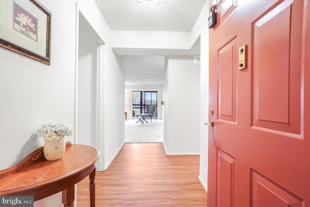 corridor with light hardwood / wood-style flooring and a textured ceiling