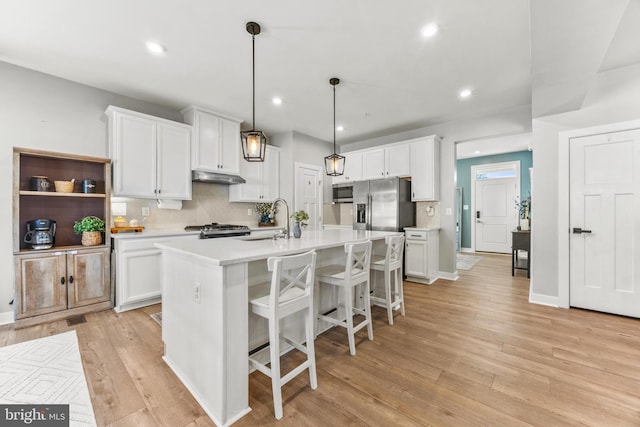 kitchen featuring decorative light fixtures, white cabinetry, and a kitchen island with sink