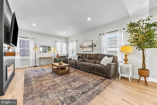 living room featuring a fireplace, light hardwood / wood-style flooring, and a healthy amount of sunlight