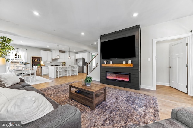 living room with a large fireplace and light hardwood / wood-style flooring