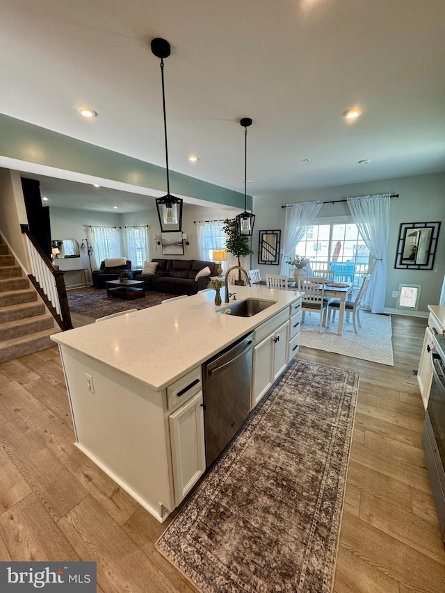 kitchen featuring dishwasher, decorative light fixtures, an island with sink, white cabinets, and sink