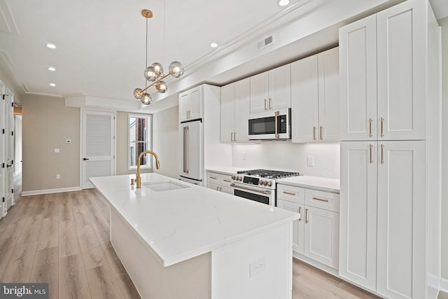 kitchen with white cabinets, a center island with sink, high end appliances, and sink