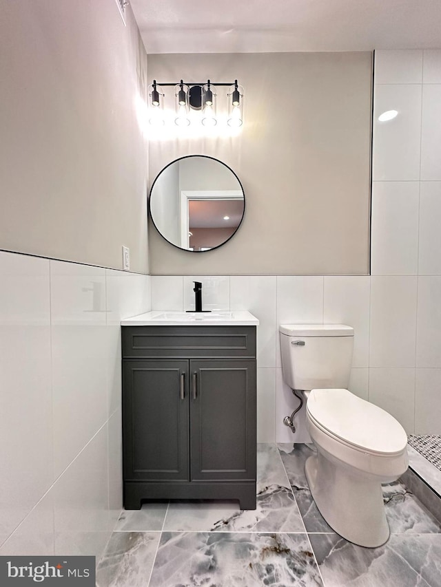 bathroom featuring vanity, toilet, and tile walls