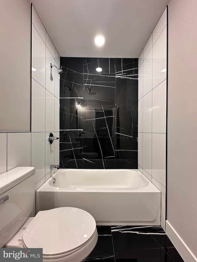 bathroom with tile patterned floors, tile walls, tiled shower / bath combo, and toilet