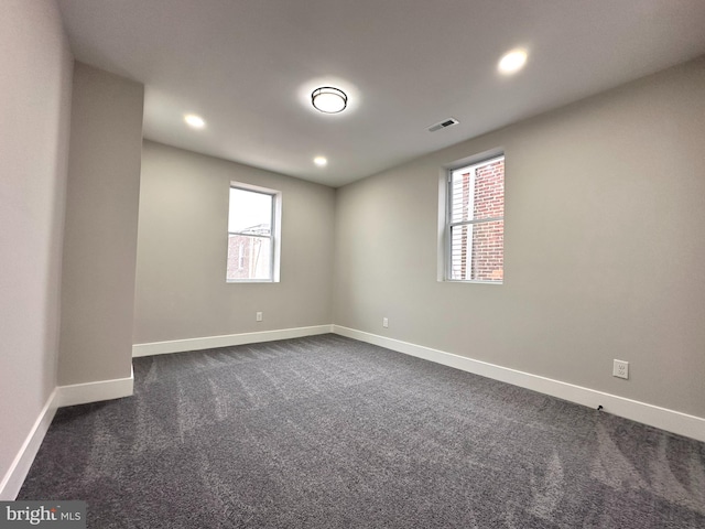 spare room featuring dark carpet