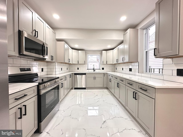 kitchen with backsplash, gray cabinets, sink, and stainless steel appliances