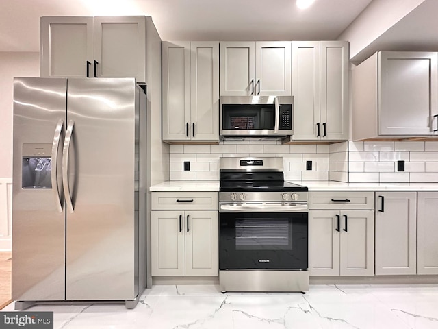 kitchen with backsplash, gray cabinetry, and stainless steel appliances