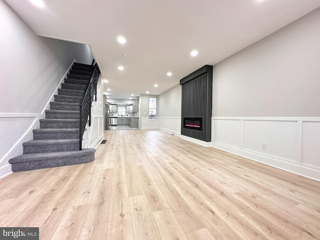 unfurnished living room with a large fireplace and light hardwood / wood-style flooring