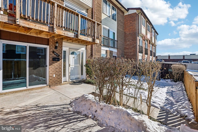 snow covered property entrance with a balcony